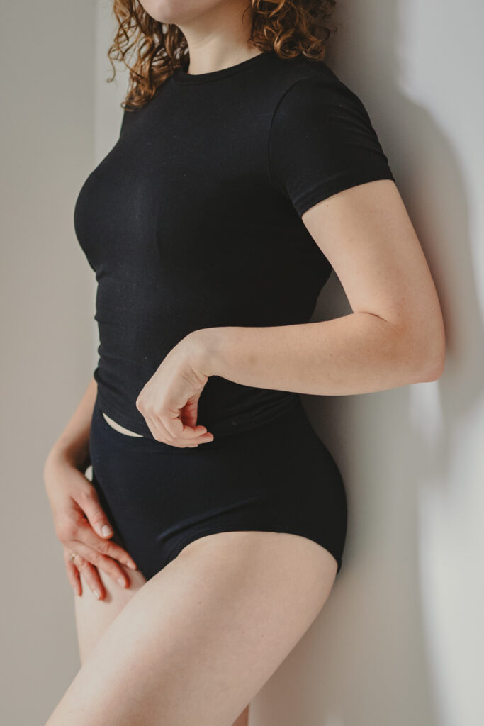 Modelka prezentująca czarny t-shirt oraz czarne majtki merino z wysokim stanem